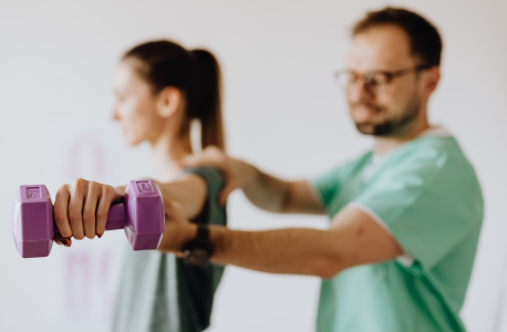 Provider examining female patient with reached arm and dumbbell